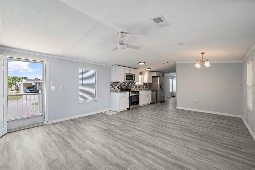 An open-concept kitchen and living area with light gray flooring, white cabinets, and a ceiling fan — 1000 KINGS HIGHWAY UNIT 101, PORT CHARLOTTE, FL