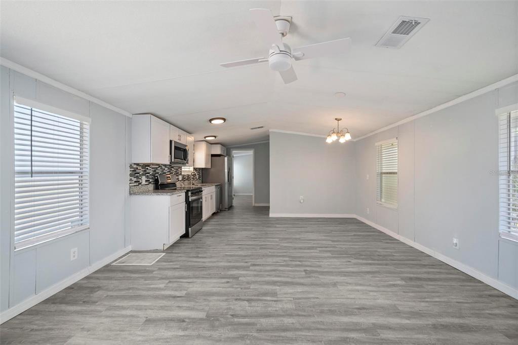 An open-concept kitchen and living area features light gray walls, wood-look flooring, and white cabinetry — 1000 KINGS HIGHWAY UNIT 101, PORT CHARLOTTE, FL