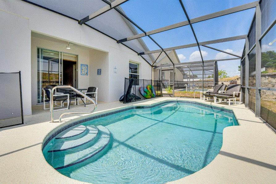 A screened-in patio features a swimming pool with built-in steps and outdoor furniture — 136 SUNSET VIEW DRIVE, DAVENPORT, FL
