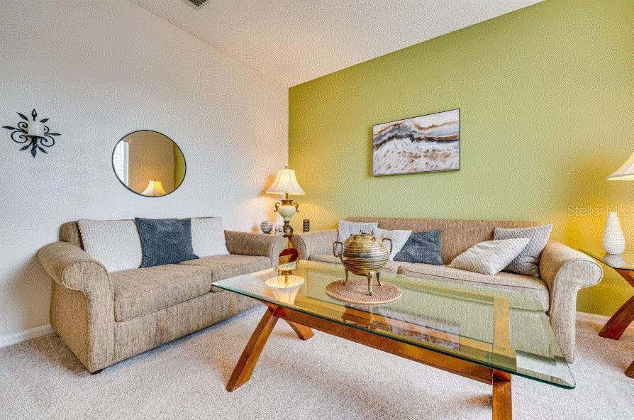 A living room features two beige sofas, a glass coffee table, and a green accent wall — 136 SUNSET VIEW DRIVE, DAVENPORT, FL