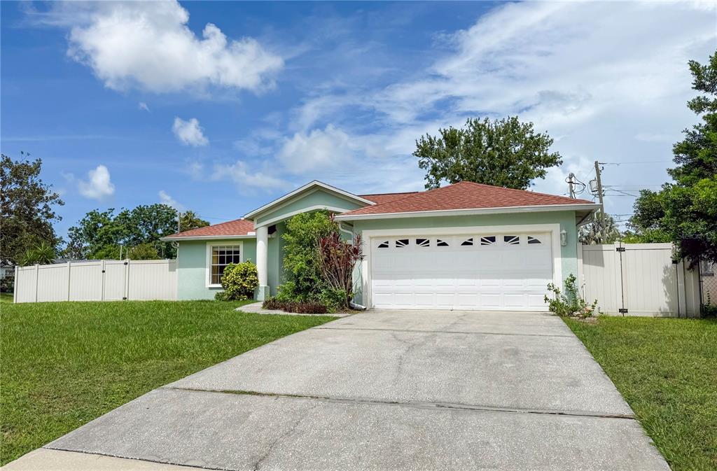 A single-story house with a light green exterior, a two-car garage, and a white fence — 29708 69TH STREET N, CLEARWATER, FL