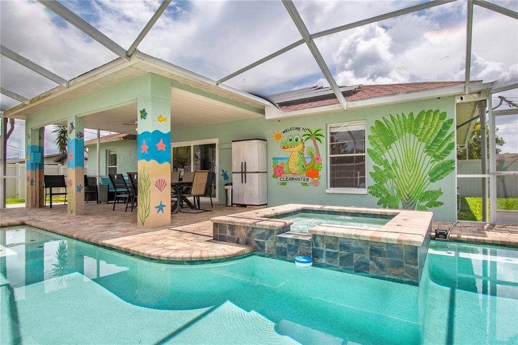 A covered patio features a swimming pool, a hot tub, and a mural of an alligator — 29708 69TH STREET N, CLEARWATER, FL