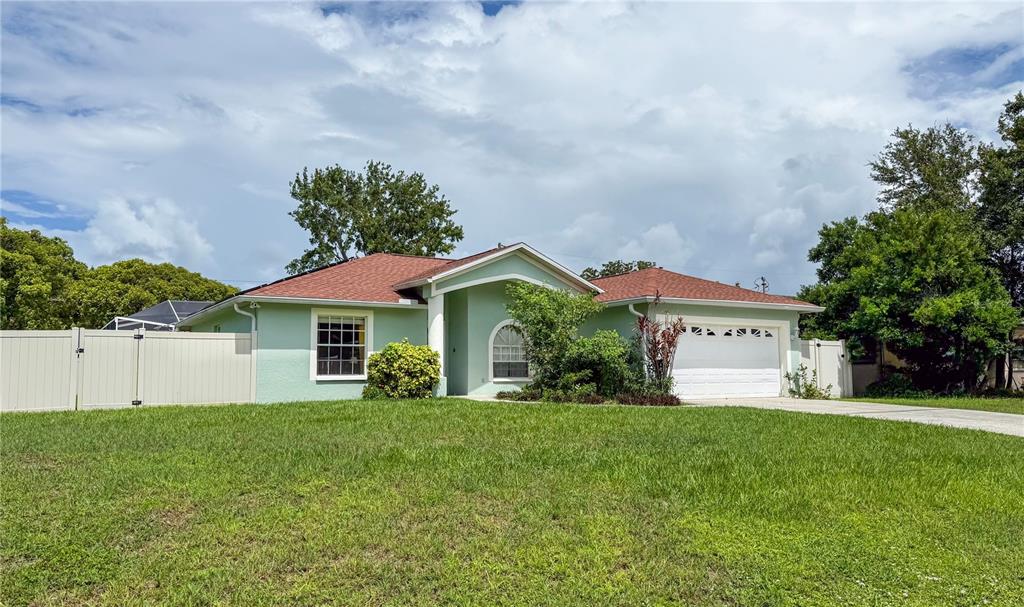 A light green single-story house with a red roof, white garage, and a white fence — 29708 69TH STREET N, CLEARWATER, FL