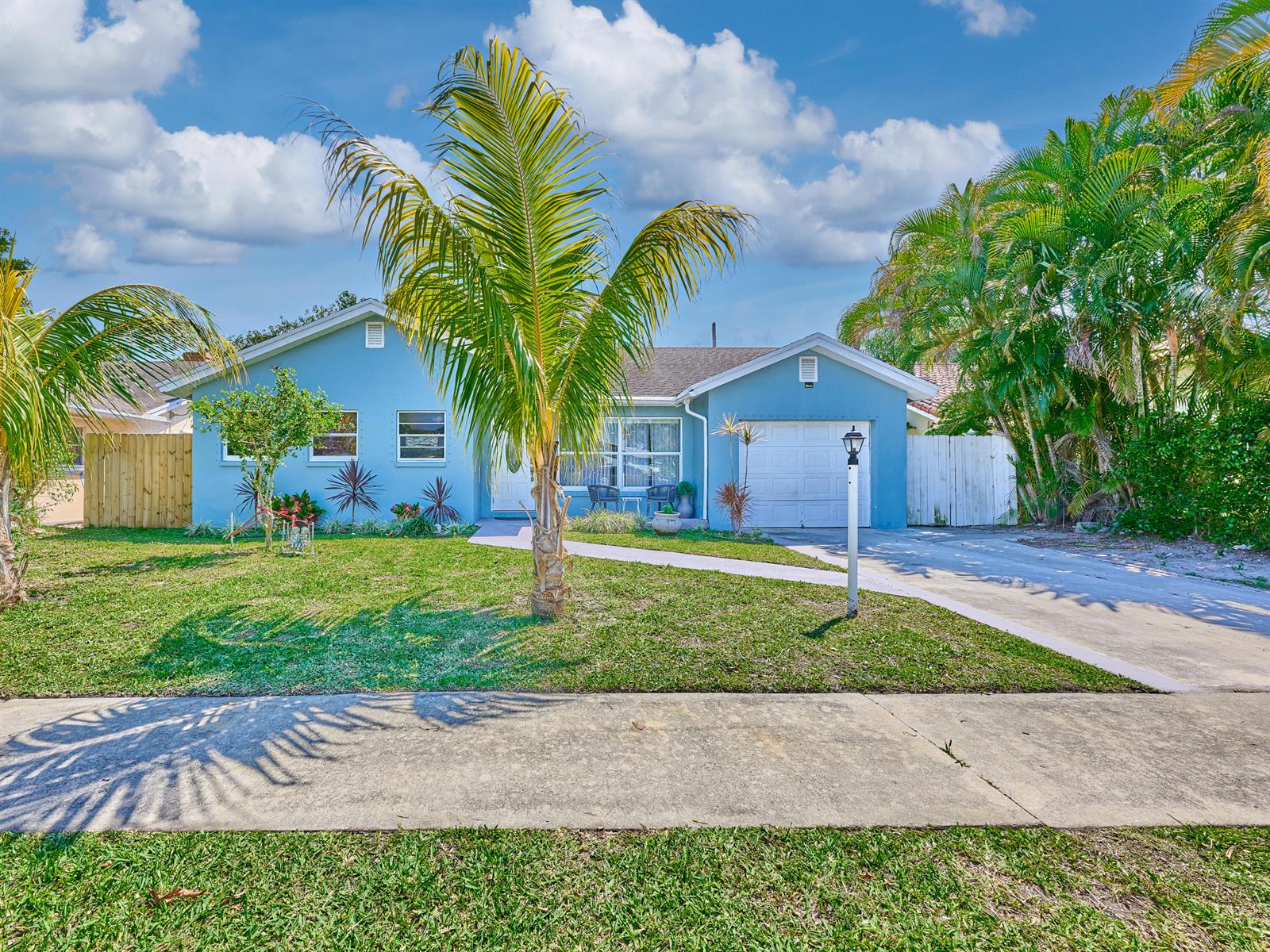 A light blue single-story house features a palm tree in the front yard and driveway — 9020 SW 8th Street, Boca Raton FL 33433, BOCA RATON, FL