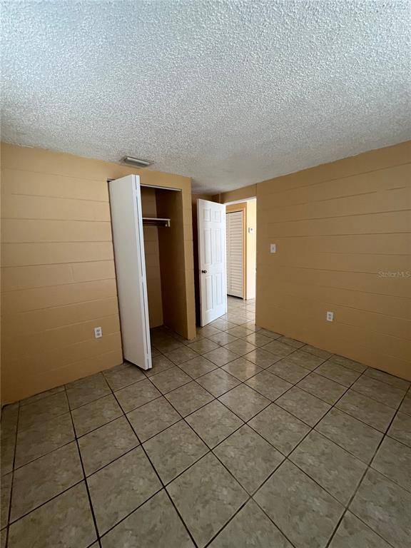 An empty room features tan block walls, a tiled floor, and two open doorways — 3007 14TH ST E, BRADENTON, FL