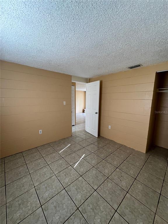 A bedroom with tan block walls, tiled floors, and a white door leading to another room — 3007 14TH ST E, BRADENTON, FL