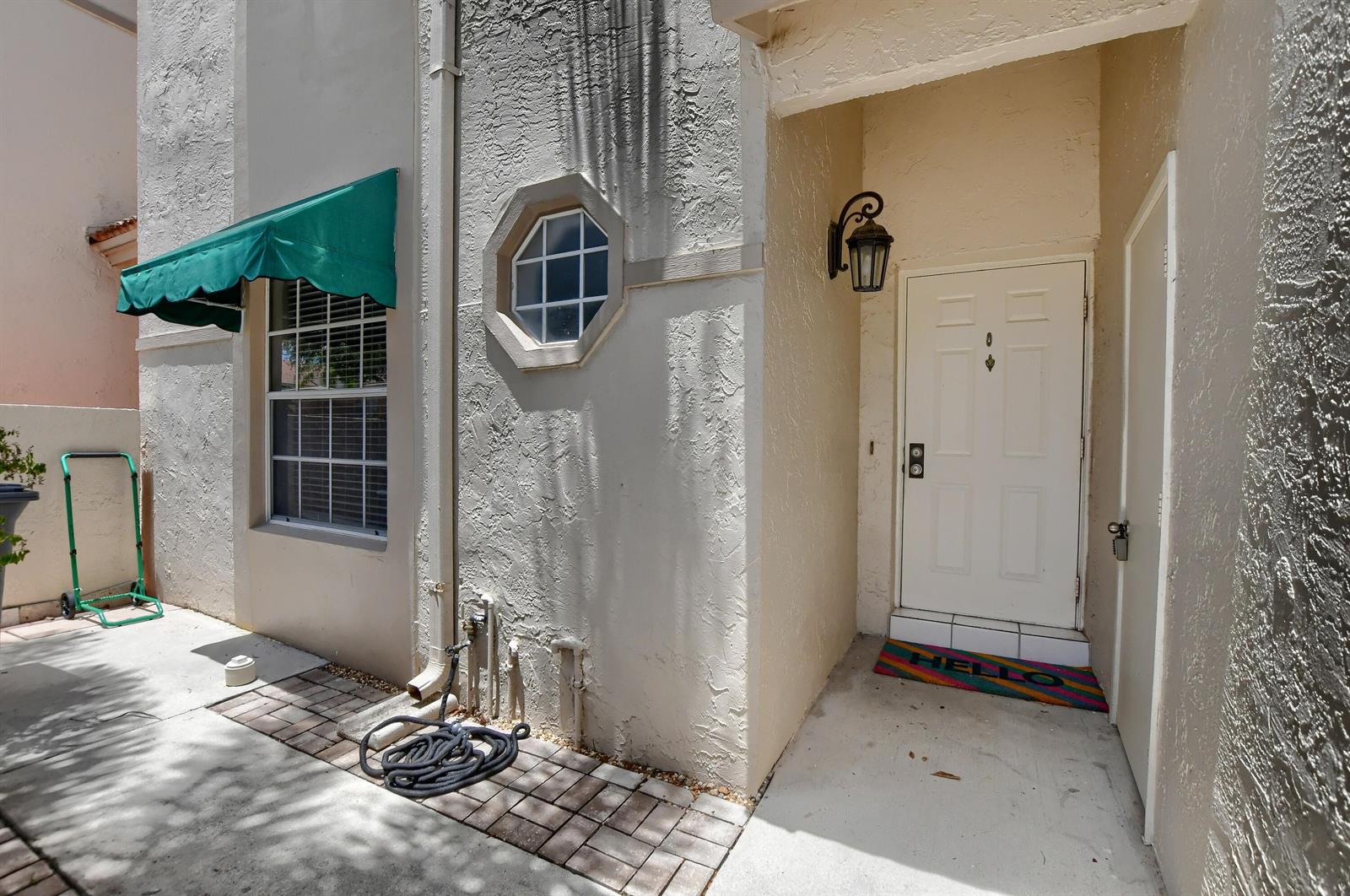 A white front door with a green awning and a small octagonal window — 6563 Via Regina, Boca Raton FL 33433, BOCA RATON, FL