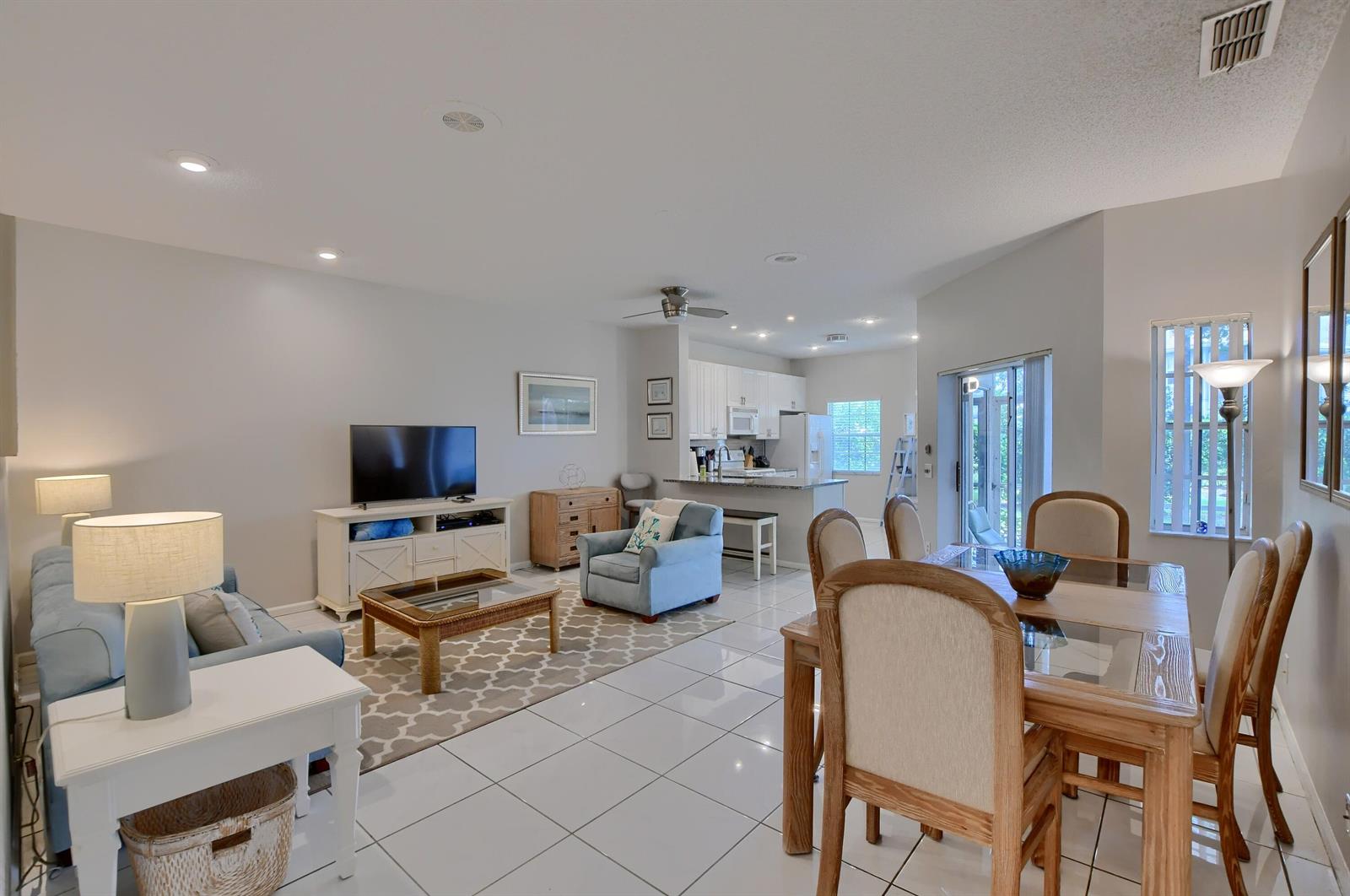 An open-concept living and dining area with white tile floors and a modern kitchen — 6563 Via Regina, Boca Raton FL 33433, BOCA RATON, FL