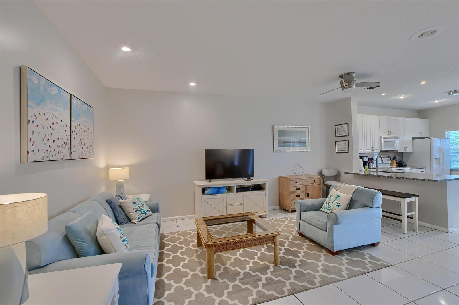 A living room with light blue furniture, a patterned rug, and an open kitchen area — 6563 Via Regina, Boca Raton FL 33433, BOCA RATON, FL