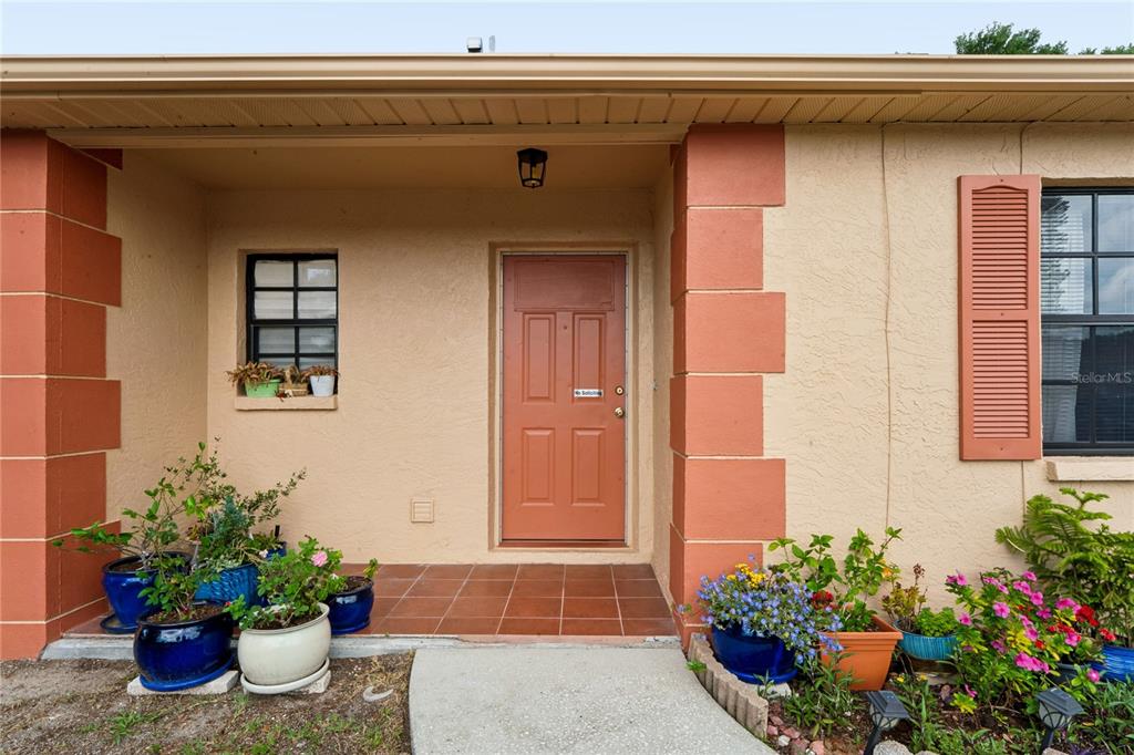The exterior of a house features a covered entryway with a tiled porch and door — 1238 FUCHSIA DRIVE, HOLIDAY, FL