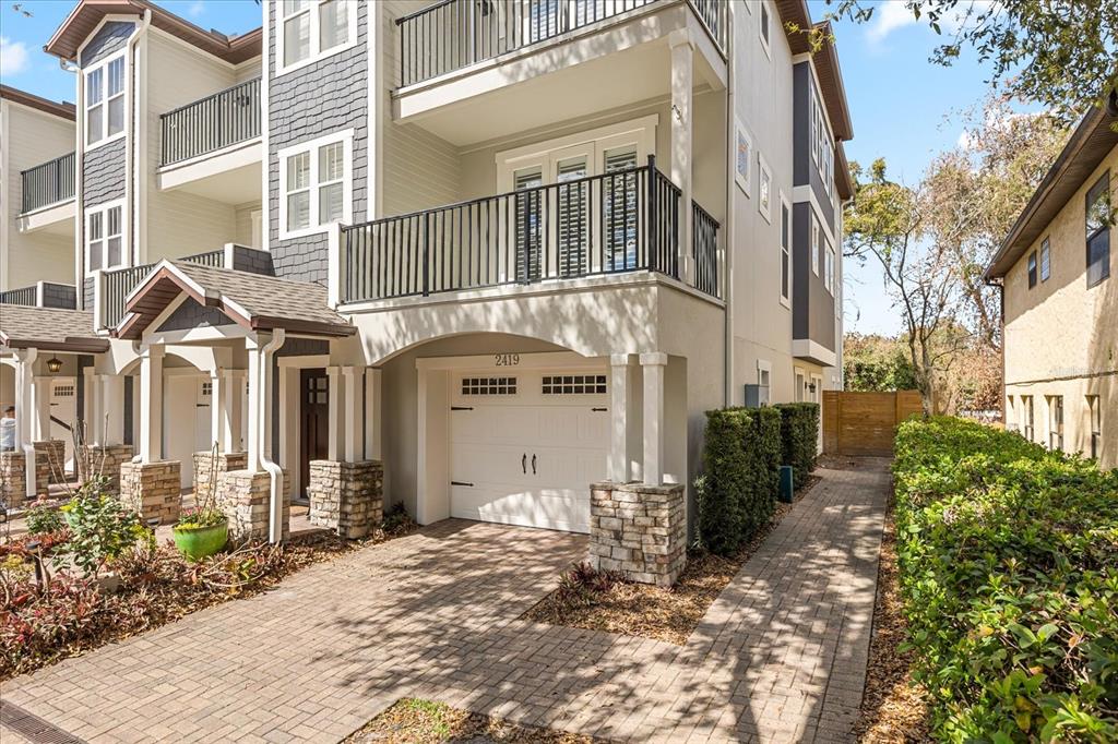 A three-story townhouse exterior with a garage, brick driveway, and second-floor balcony — 2419 KILGORE STREET, ORLANDO, FL