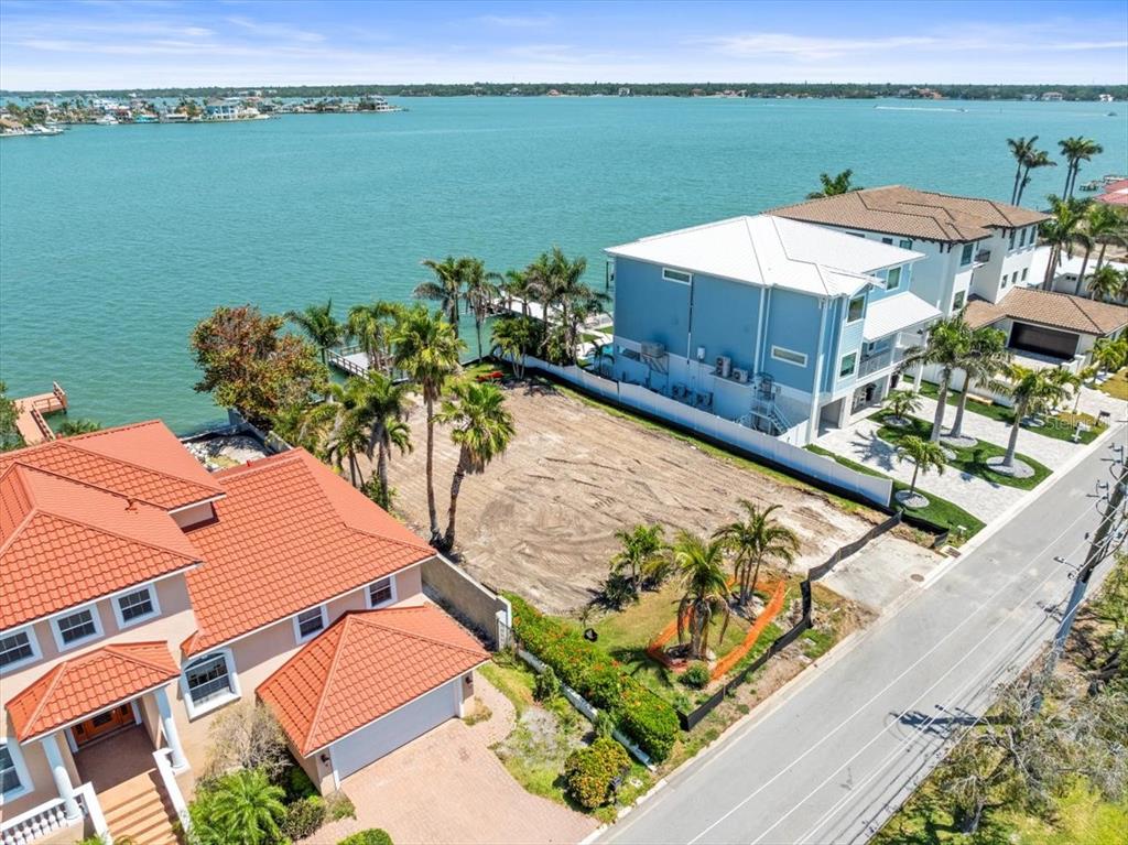 An aerial view shows a vacant waterfront lot situated between two large residential homes — 6 PARADISE LANE, TREASURE ISLAND, FL