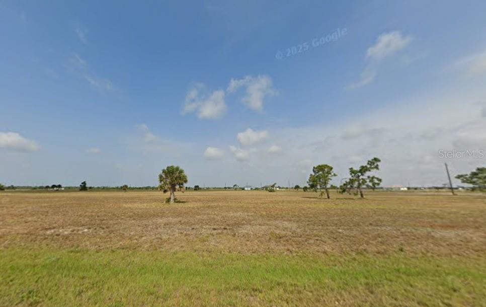 A wide, flat, grassy field under a blue sky with scattered clouds — 13 COCKATIEL WAY, PLACIDA, FL