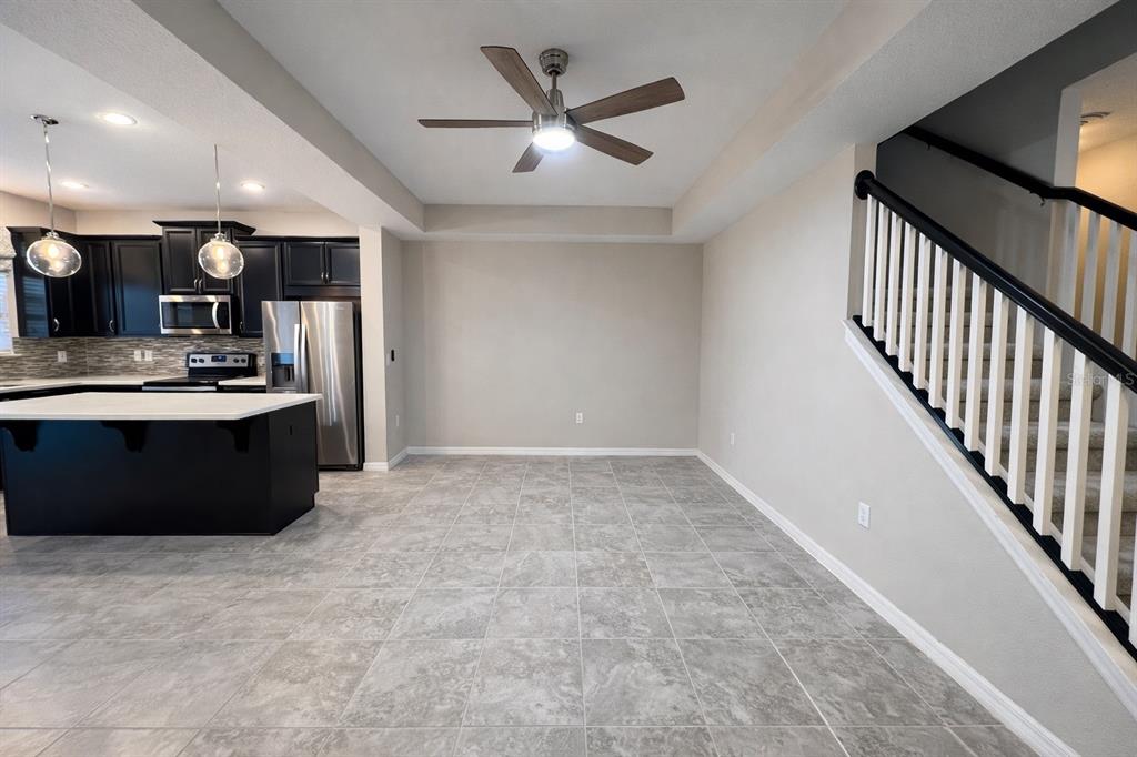 An open dining area features gray tile flooring, a ceiling fan, and an adjacent kitchen — 3749 BRIGHTON PARK CIRCLE, ORLANDO, FL