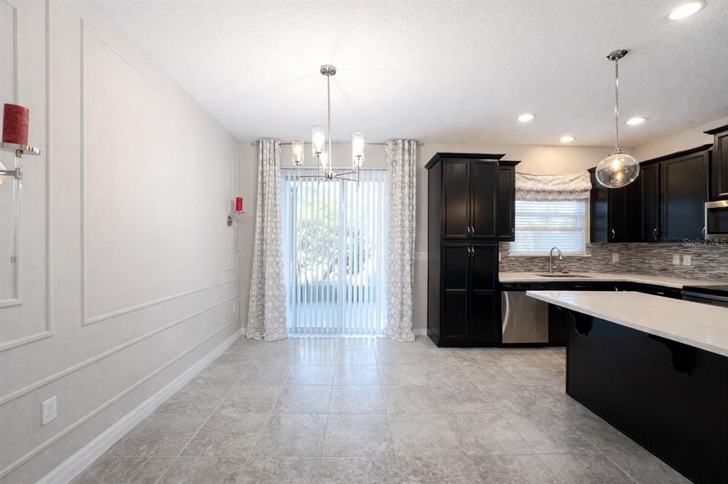 A dining area with tile flooring, a chandelier, and a kitchen with dark cabinets — 3749 BRIGHTON PARK CIRCLE, ORLANDO, FL