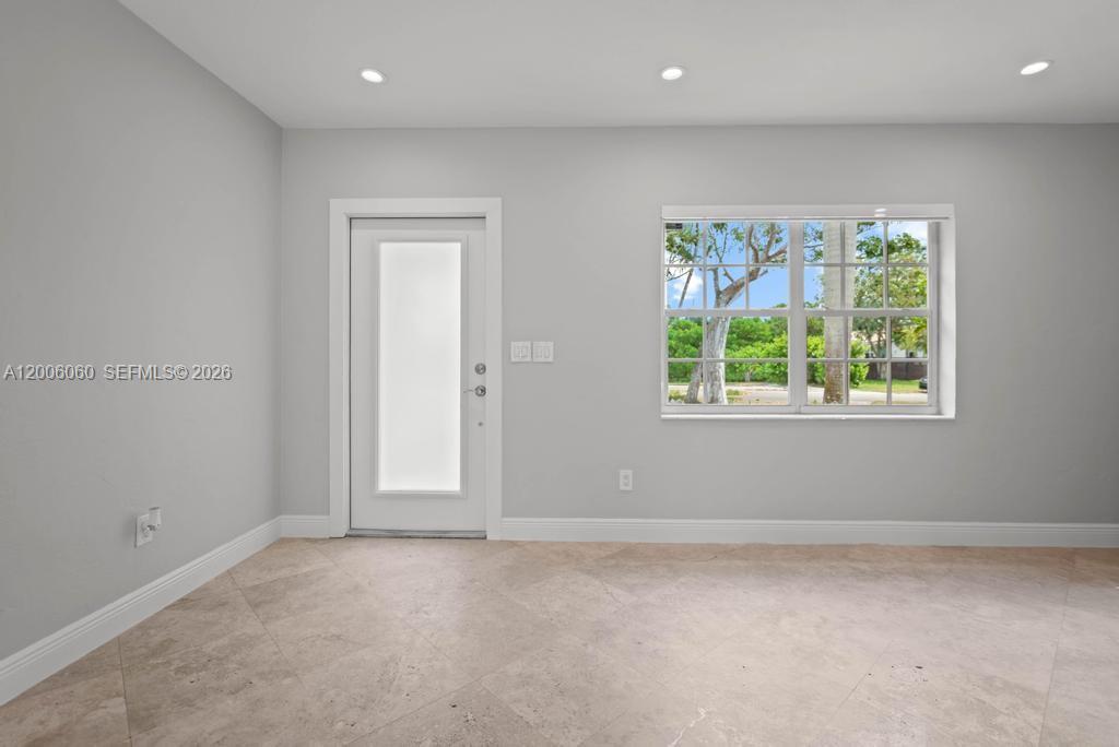 A room with light gray walls, tile flooring, a white door, and a window — 11222 NE 9th Ave, Biscayne Park FL 33161, BISCAYNE PARK, FL
