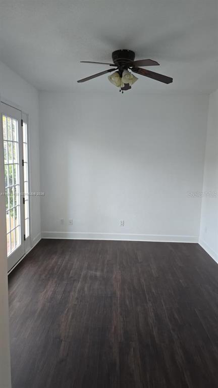 An empty room with dark wood-look flooring, white walls, a ceiling fan, and glass doors — 2802 QUIET WATER TRAIL, KISSIMMEE, FL