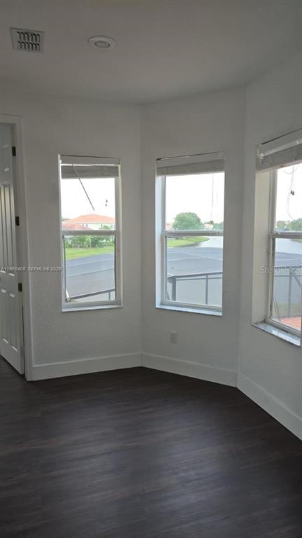 A room with dark wood-look flooring, white walls, and three windows overlooking a lake — 2802 QUIET WATER TRAIL, KISSIMMEE, FL