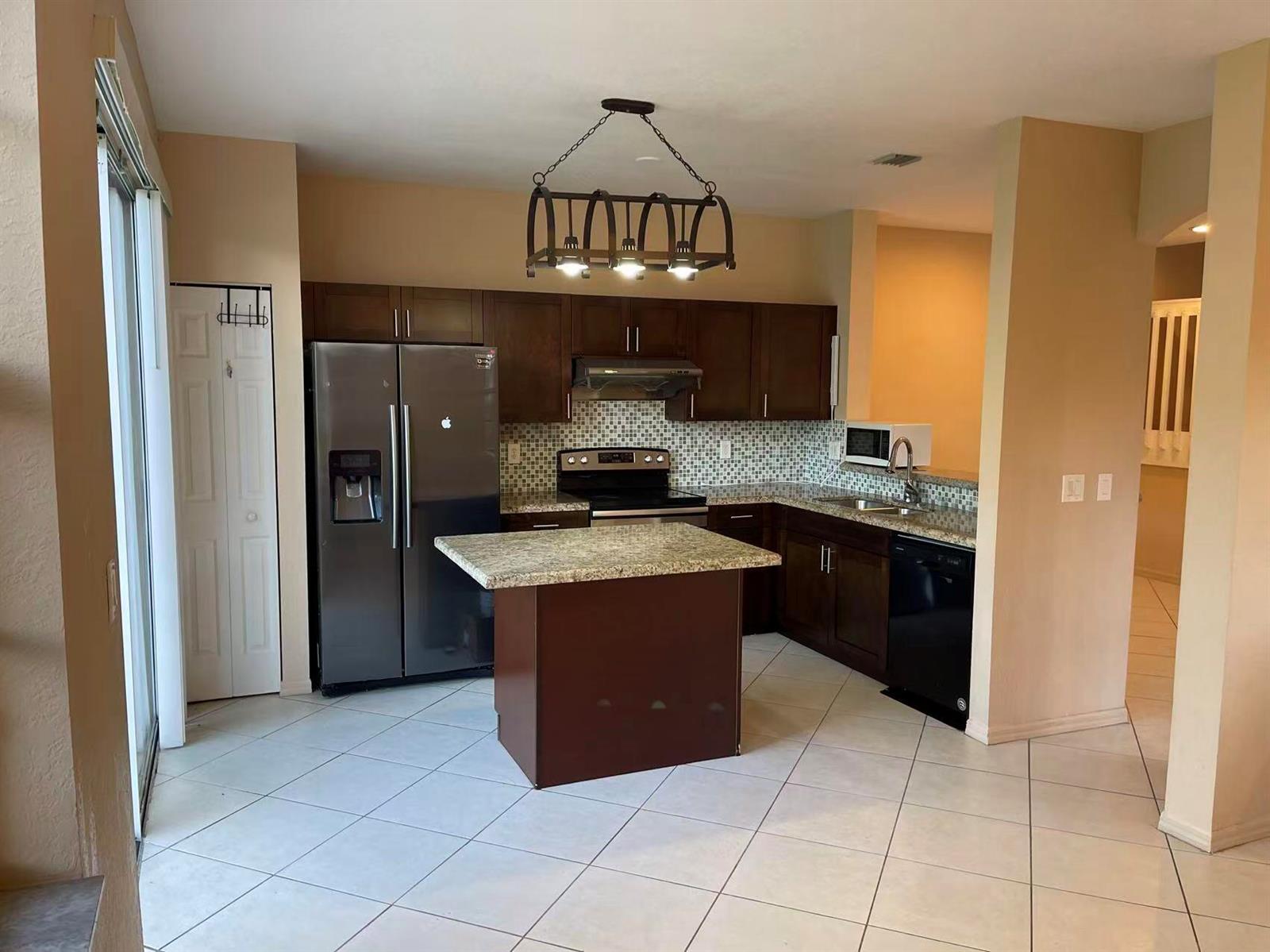 A kitchen with dark wood cabinets, granite countertops, a center island, and tile flooring — 4061 NW 91st Terrace, Sunrise FL 33351, SUNRISE, FL