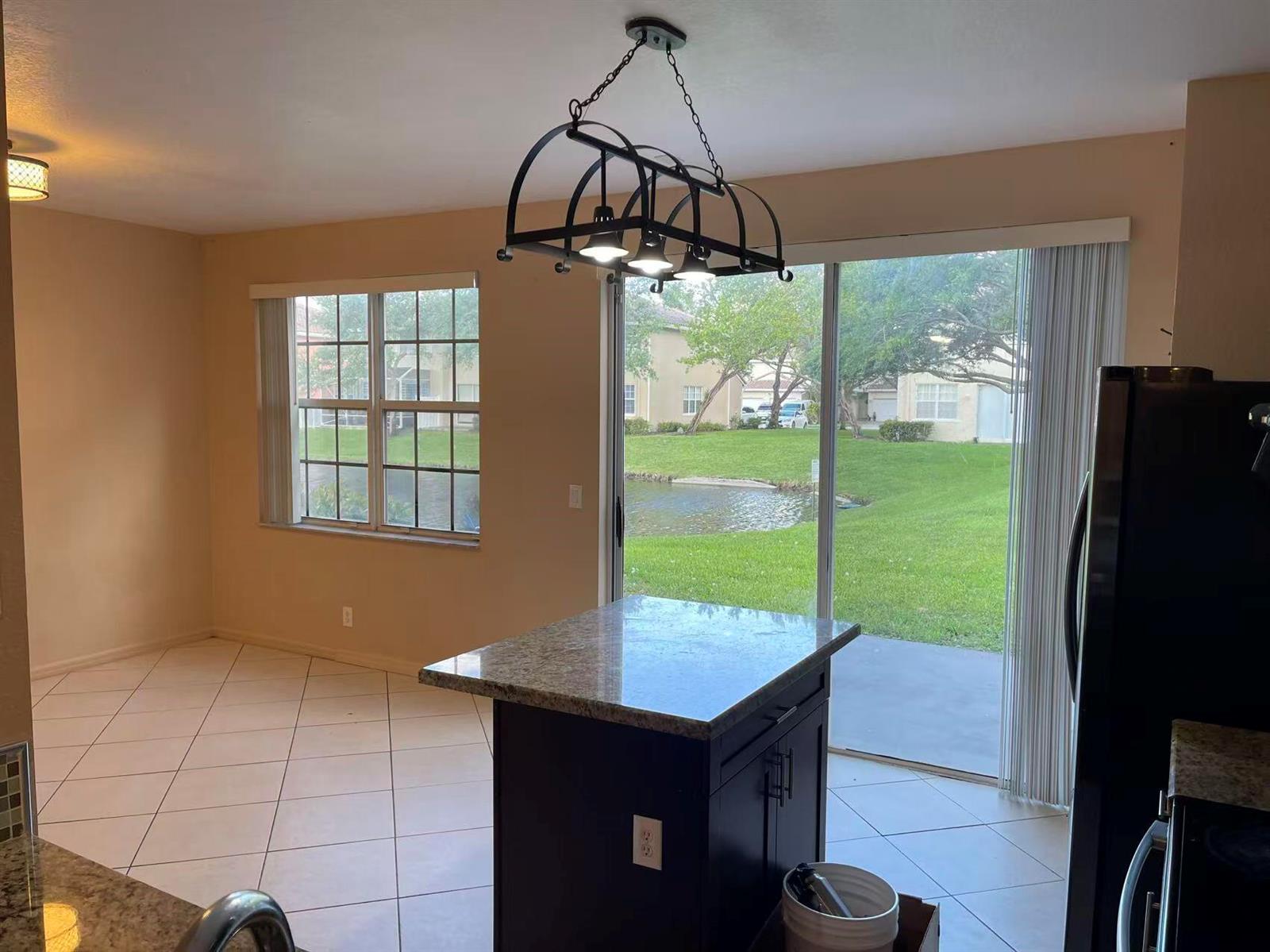 A kitchen island with a granite countertop sits in a room with tile flooring and windows — 4061 NW 91st Terrace, Sunrise FL 33351, SUNRISE, FL
