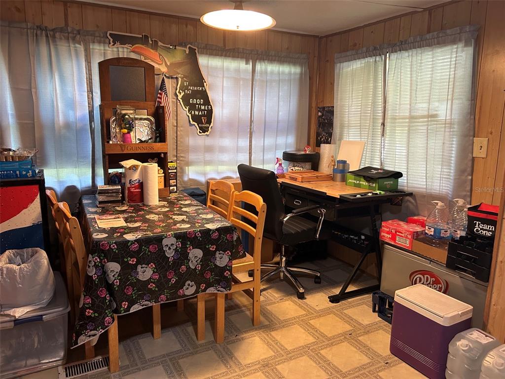 A dining area with a skull-patterned tablecloth, wooden chairs, and a desk near windows — 10945 SE 132ND PLACE, OCKLAWAHA, FL