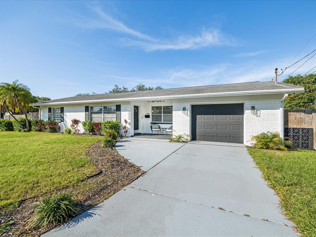 A single-story white brick house features a grey garage door and a concrete driveway — 2000 57TH STREET N, ST PETERSBURG, FL