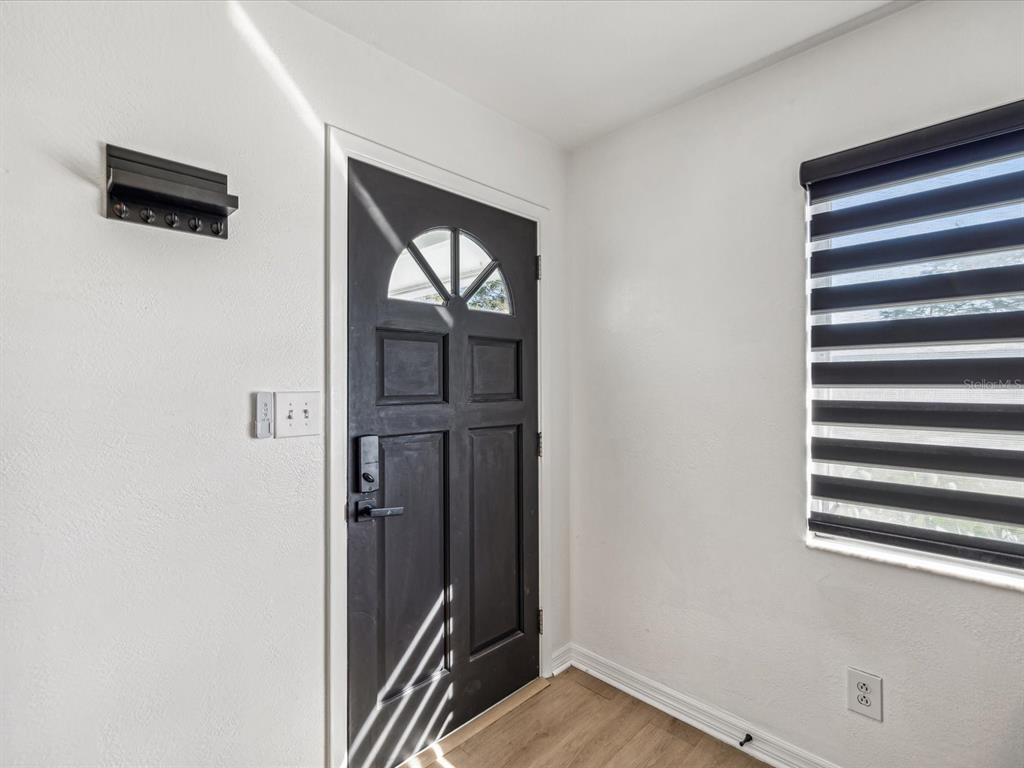 An entryway features a black front door, light wood flooring, and a window with blinds — 2000 57TH STREET N, ST PETERSBURG, FL