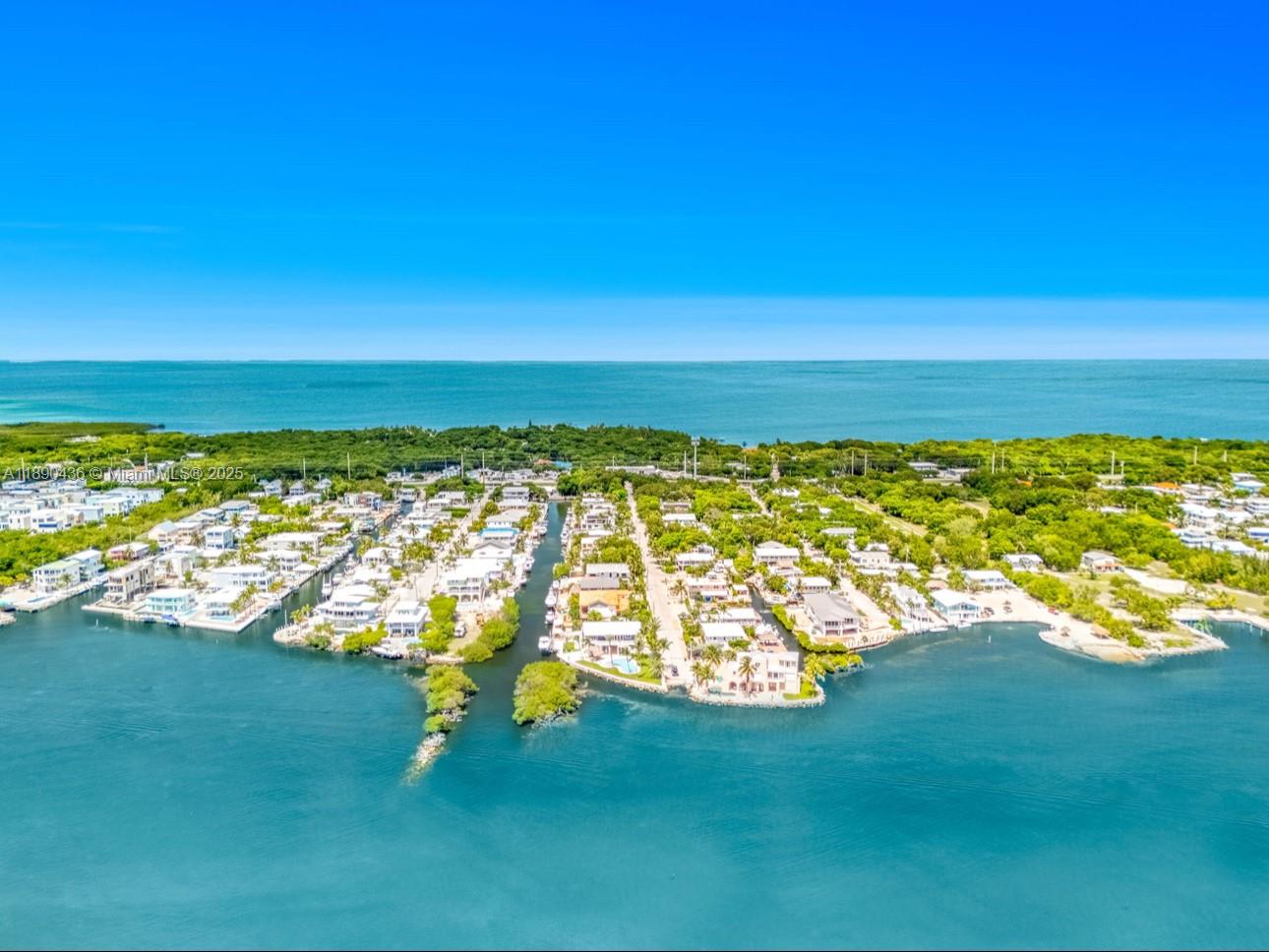 An aerial view shows a coastal neighborhood with houses lining a canal and lush greenery — 1032 Snapper Ln, Key Largo FL 33037, KEY LARGO, FL
