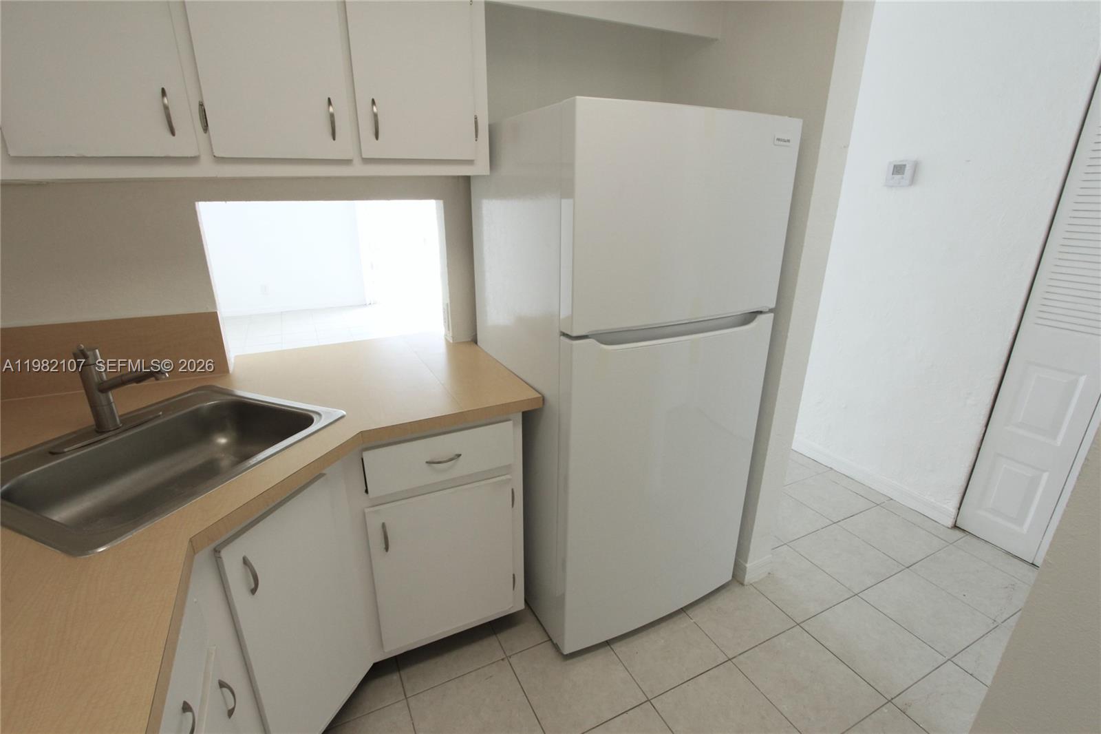 A kitchen features white cabinets, a stainless steel sink, and a white refrigerator — 4550 NW 9th St # 815E, Miami FL 33126, MIAMI, FL