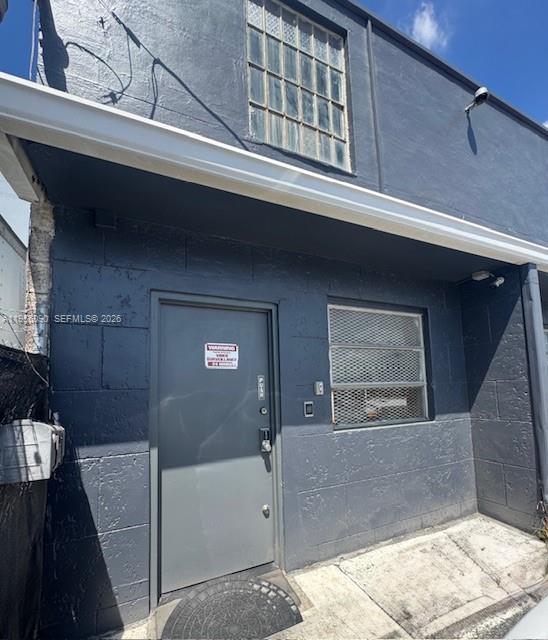 A gray concrete building exterior features a metal door and a window with security bars — 7130 NW 35th Ave, Miami FL 33147, MIAMI, FL