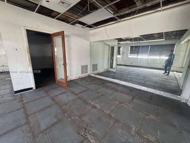 An interior room features a wooden door, mirrored walls, and exposed ceiling grid panels — 7130 NW 35th Ave, Miami FL 33147, MIAMI, FL