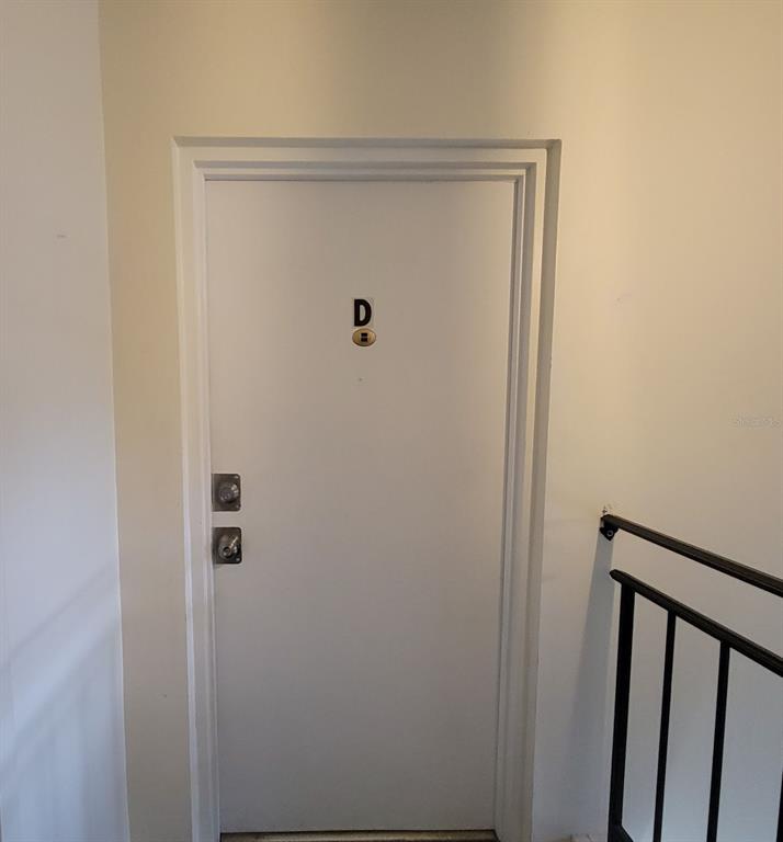 A white door labeled with the letter D features two locks and a peephole — 1143 85TH TERRACE N UNIT D, ST PETERSBURG, FL