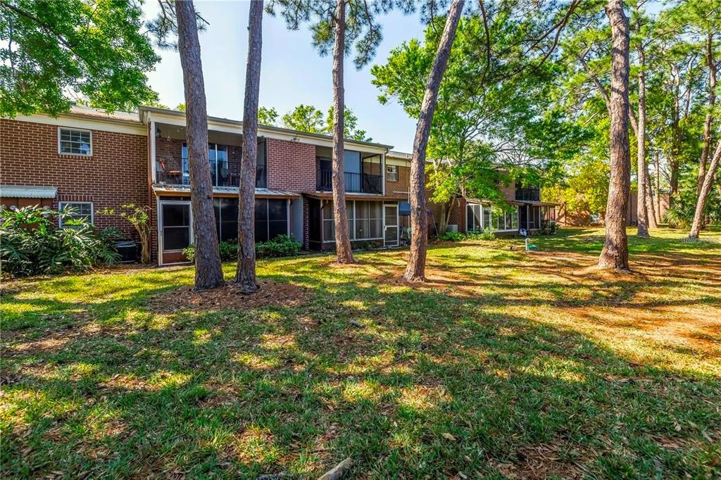 A two-story brick apartment building features screened-in patios and balconies overlooking a grassy yard — 1143 85TH TERRACE N UNIT D, ST PETERSBURG, FL