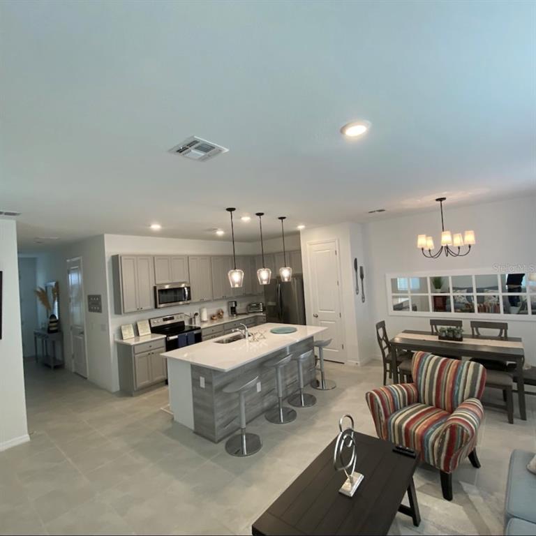 An open-concept kitchen and dining area featuring a central island, gray cabinetry, and tile flooring — 1546 DISCOVERY STREET, DAVENPORT, FL