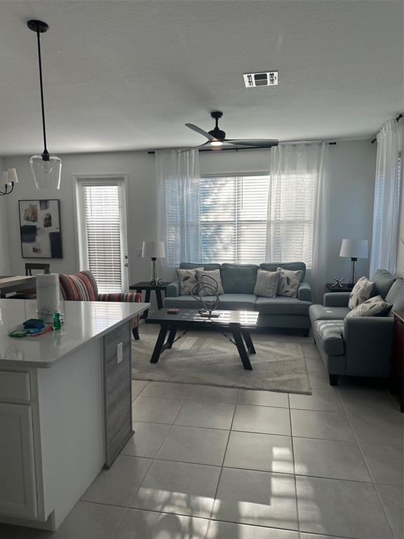 A living room features light blue sofas, a coffee table, and tile flooring — 1546 DISCOVERY STREET, DAVENPORT, FL