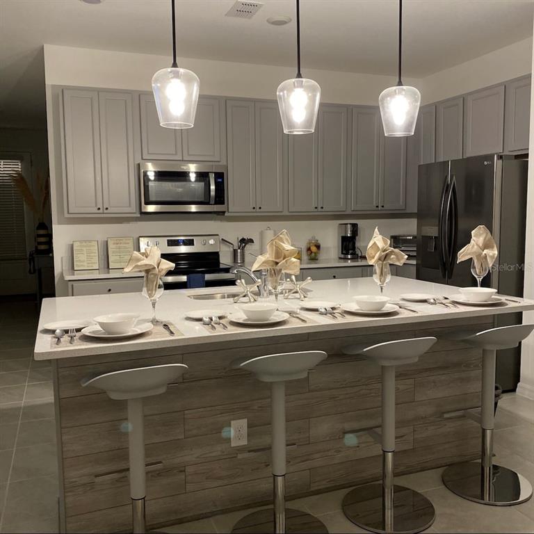 A kitchen features gray cabinets, stainless steel appliances, and a large island with bar seating — 1546 DISCOVERY STREET, DAVENPORT, FL