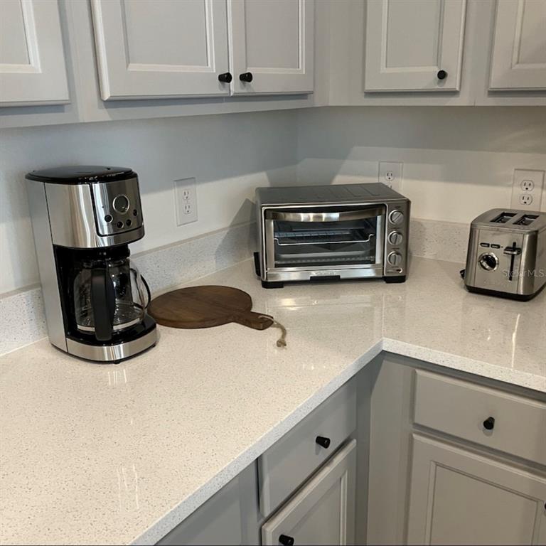 A kitchen counter features a coffee maker, toaster oven, and toaster with grey cabinets — 1546 DISCOVERY STREET, DAVENPORT, FL