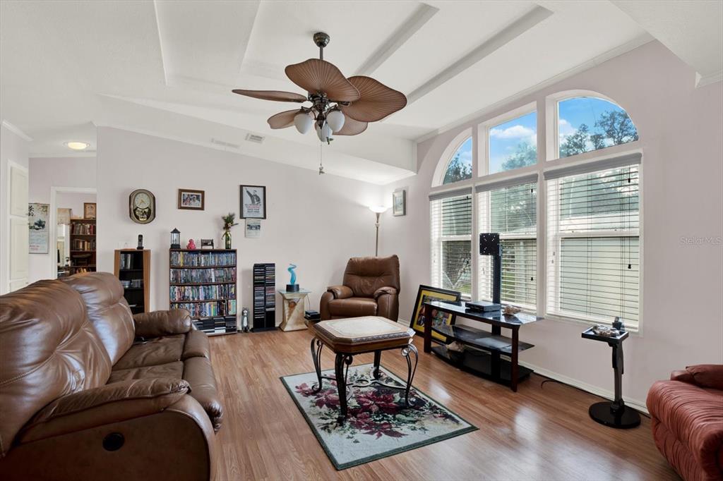 A living room with wood-look flooring, a ceiling fan, and large windows with blinds — 8010 CEDAR COVE AVENUE, BROOKSVILLE, FL