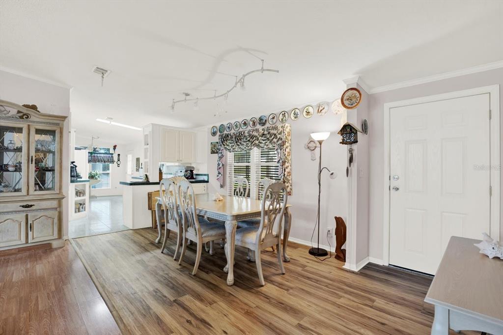 A dining area features wood-look flooring, a table with four chairs, and a white door — 8010 CEDAR COVE AVENUE, BROOKSVILLE, FL