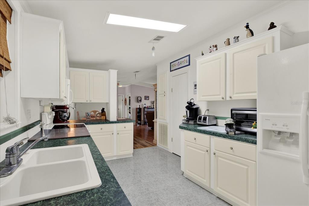 A kitchen features white cabinets, green countertops, a double sink, and a white refrigerator — 8010 CEDAR COVE AVENUE, BROOKSVILLE, FL