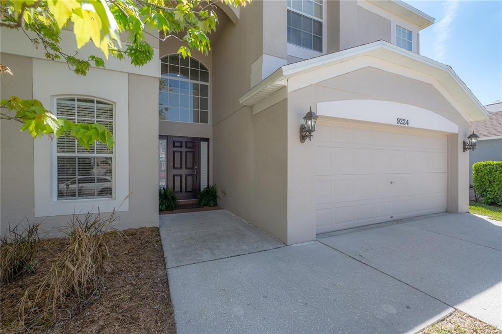 The exterior of a two-story house features a beige stucco facade, a garage, and an entryway — 9224 LOST MILL DRIVE, LAND O LAKES, FL