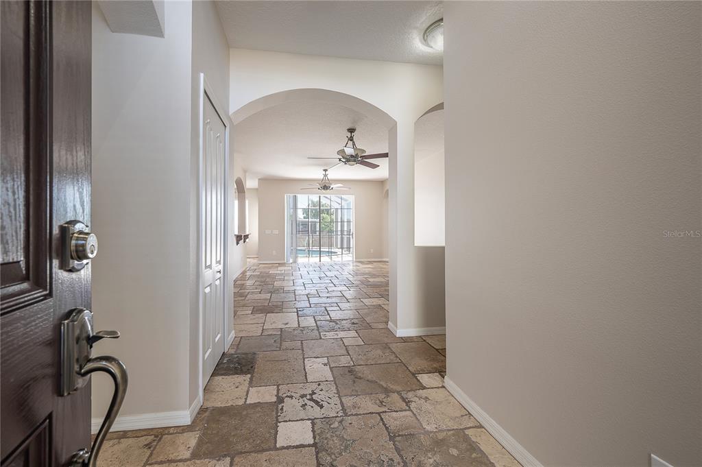 A tiled entryway leads through an arched opening toward a living area with a pool view — 9224 LOST MILL DRIVE, LAND O LAKES, FL