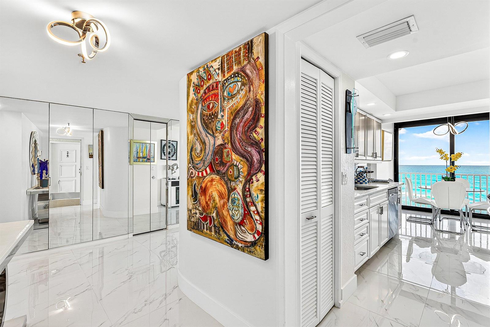 A bright hallway with marble floors leads to a kitchen overlooking the ocean — 3360 S Ocean Boulevard, Palm Beach FL 33480, PALM BEACH, FL