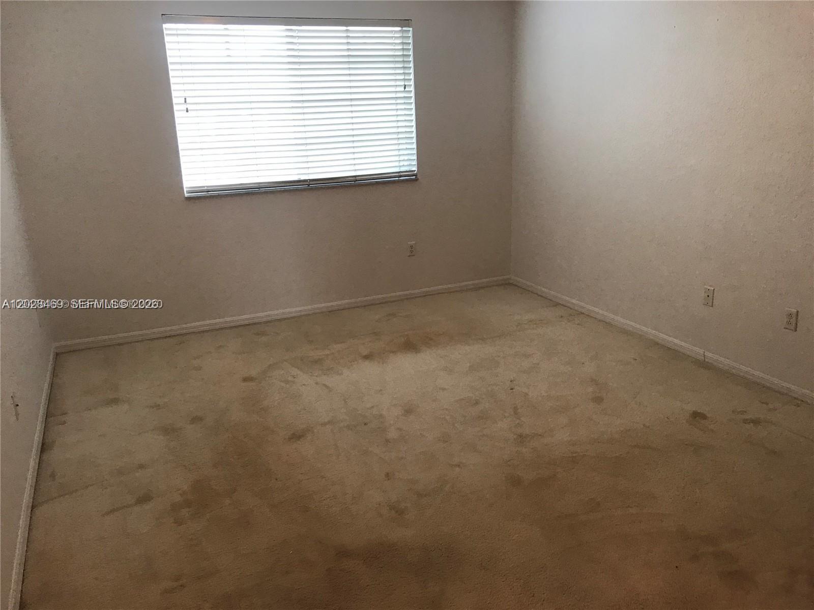 An empty bedroom features beige carpet, white walls, and a window with closed blinds — 5743 NW 114th Path # 106, Doral FL 33178, DORAL, FL