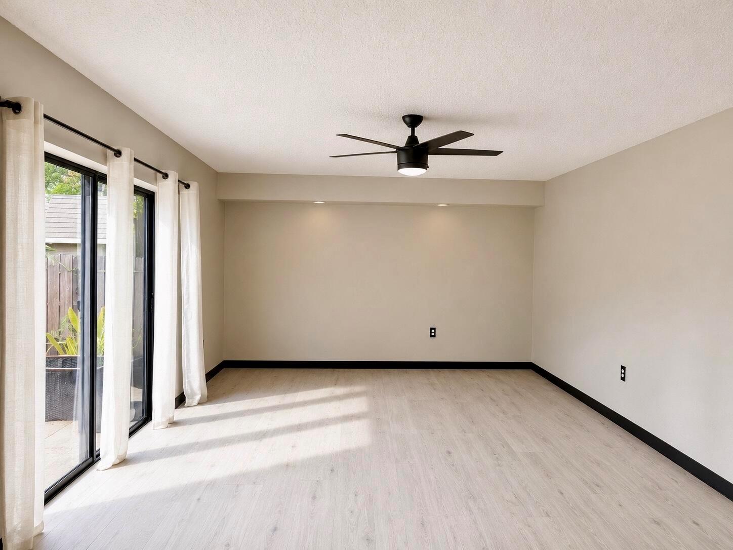 An empty room with light wood floors, a ceiling fan, and sliding glass patio doors — 1303 13th Way, West Palm Beach FL 33407, WEST PALM BEACH, FL