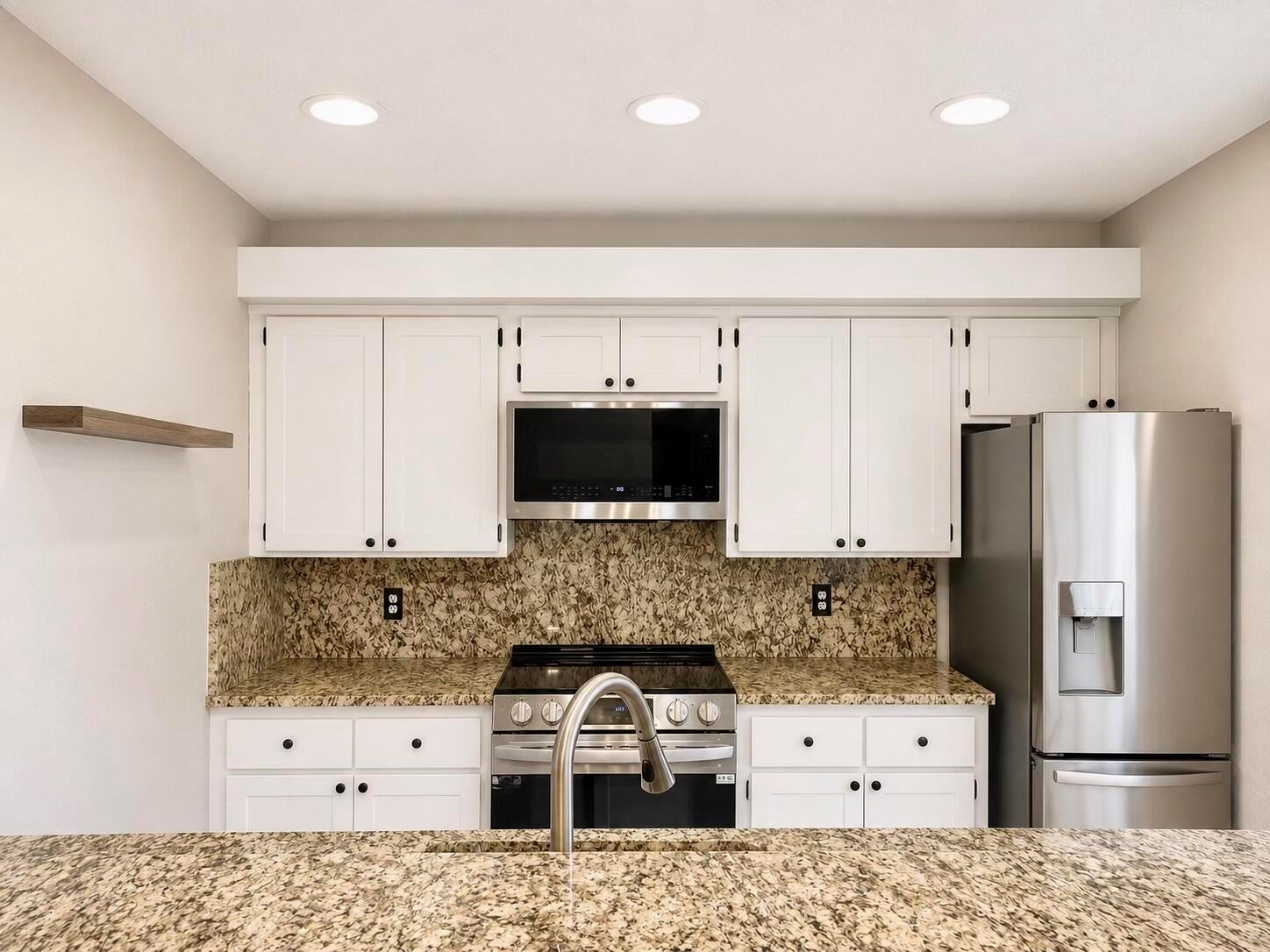 A kitchen with white cabinets, granite countertops, stainless steel appliances, and a floating wood shelf — 1303 13th Way, West Palm Beach FL 33407, WEST PALM BEACH, FL