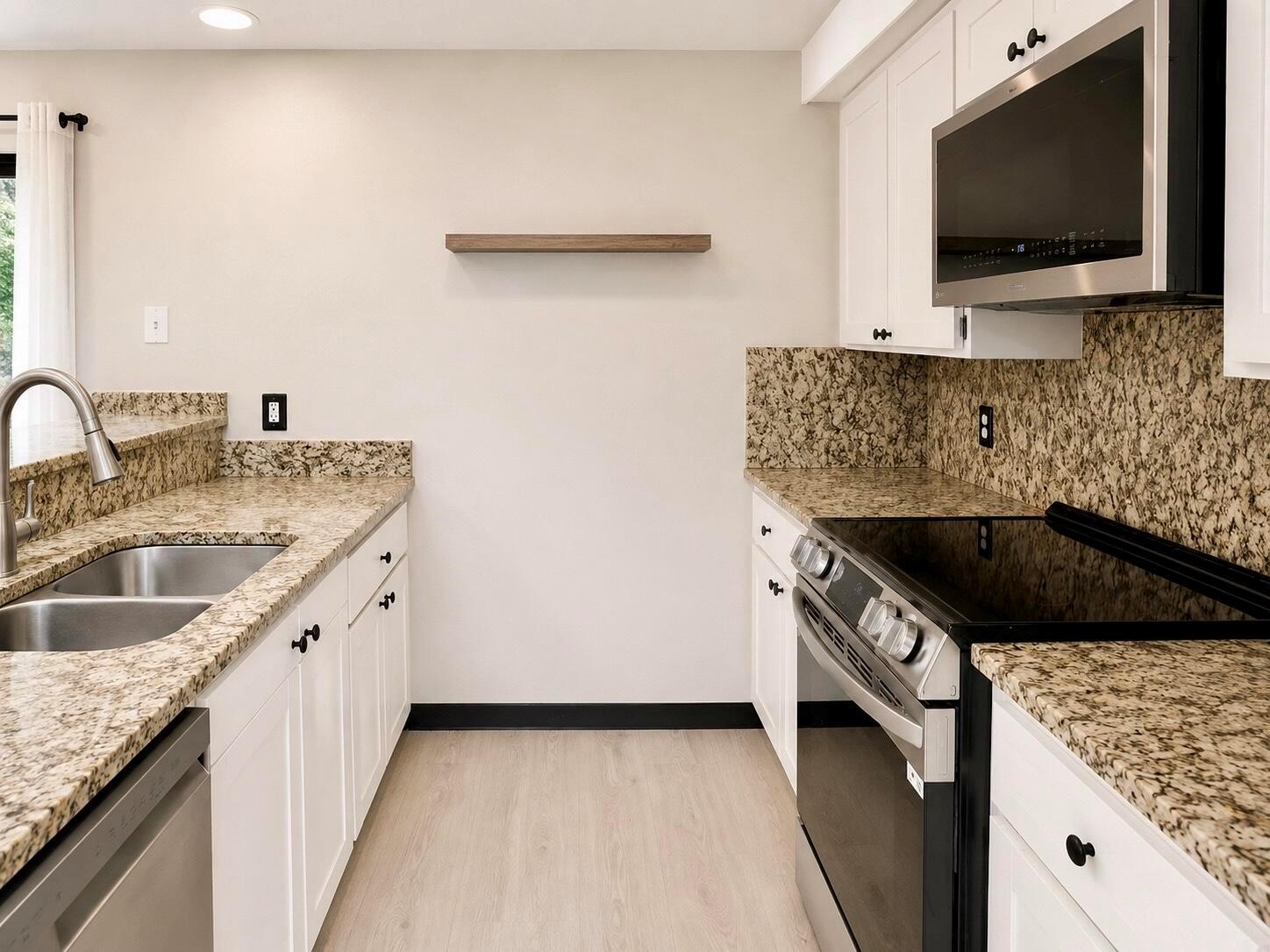 A kitchen features white cabinets, granite countertops, stainless steel appliances, and a single floating wood shelf — 1303 13th Way, West Palm Beach FL 33407, WEST PALM BEACH, FL