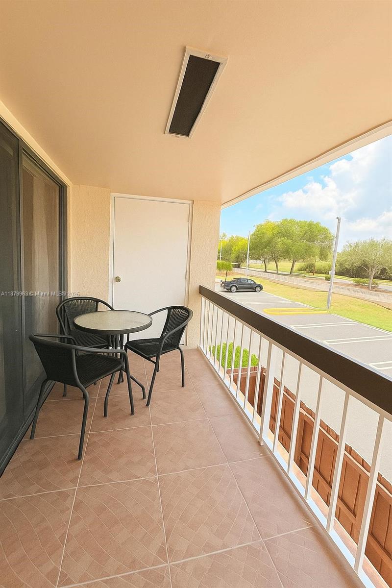 A balcony features tiled flooring, a small table with three chairs, and a metal railing — 13781 SW 66th St # 221B, Miami FL 33183, MIAMI, FL