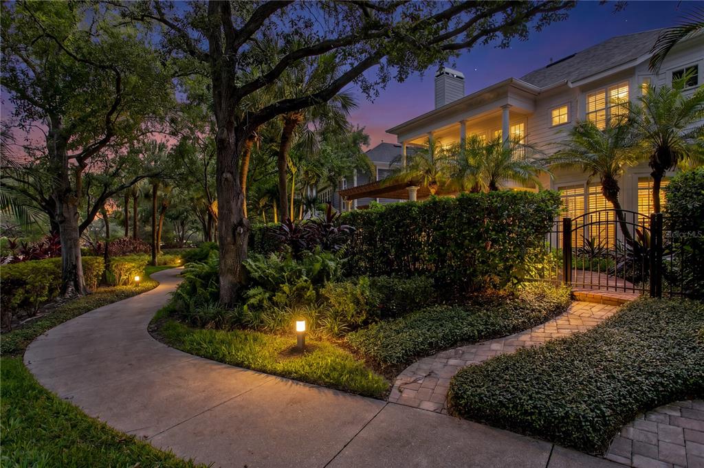 A paved walkway leads to a two-story house with a fenced patio and lush landscaping — 905 HARBOUR BAY DRIVE, TAMPA, FL