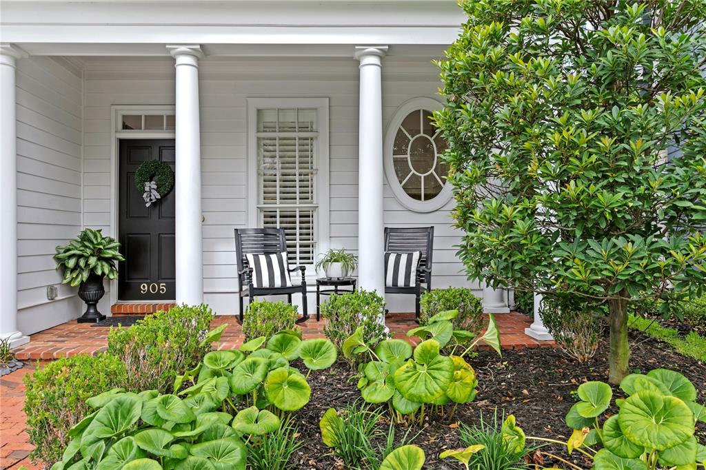 A front porch features a black door, two rocking chairs, and white columns — 905 HARBOUR BAY DRIVE, TAMPA, FL